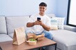 © Krakenimages.com - Young hispanic man make photo by smartphone to take away food at home