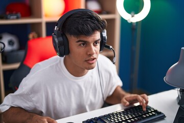 Canvas Print - Young hispanic man streamer playing video game using computer at gaming room