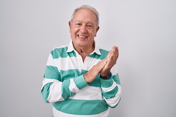 Poster - Senior man with grey hair standing over white background clapping and applauding happy and joyful, smiling proud hands together