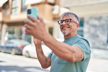 Poster - Middle age grey-haired man smiling confident having video call at street