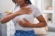 © Krakenimages.com - African american woman examining breast sitting on sofa at home