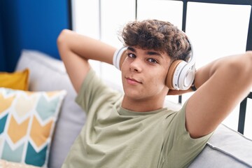 Poster - Young hispanic teenager listening to music relaxed on sofa at home