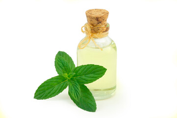 Glass bottle of peppermint essential oil with fresh green mint leaves isolated on white background