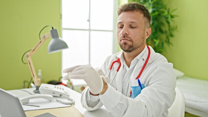 Poster - Young man doctor using laptop wearing gloves at clinic