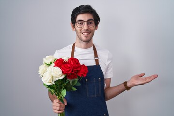 Poster - Young hispanic man holding bouquet of white and red roses pointing aside with hands open palms showing copy space, presenting advertisement smiling excited happy