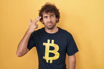 Canvas Print - Hispanic young man wearing bitcoin t shirt shooting and killing oneself pointing hand and fingers to head like gun, suicide gesture.