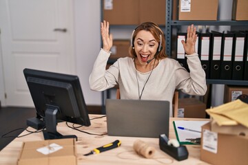 Canvas Print - Hispanic woman working at small business ecommerce wearing headset celebrating victory with happy smile and winner expression with raised hands