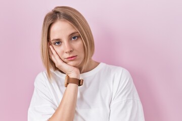 Canvas Print - Young caucasian woman standing over pink background thinking looking tired and bored with depression problems with crossed arms.