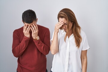 Canvas Print - Mother and son standing together over isolated background with sad expression covering face with hands while crying. depression concept.