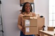 © Krakenimages.com - Young african american with braids working at small business ecommerce holding packages smiling and laughing hard out loud because funny crazy joke.