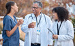© Tshidzumba/peopleimages.com - Coffee break, talking and doctors for healthcare planning, happy conversation and outdoor advice from mentor. Internship, funny and social life of medical women, nurses and clinic staff with drink
