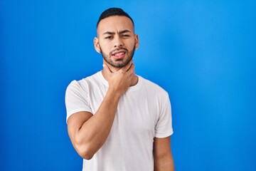 Poster - Young hispanic man standing over blue background touching painful neck, sore throat for flu, clod and infection