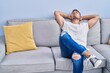 © Krakenimages.com - Young hispanic man relaxed with hands on head sitting on sofa at home