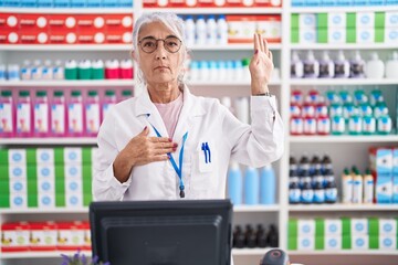 Canvas Print - Middle age woman with tattoos working at pharmacy drugstore swearing with hand on chest and open palm, making a loyalty promise oath