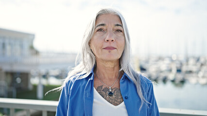 Poster - Middle age grey-haired woman standing with serious expression at seaside