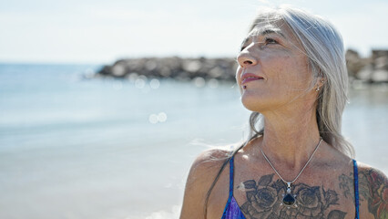 Poster - Middle age grey-haired woman tourist wearing bikini standing with relaxed expression at beach