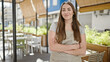 © Krakenimages.com - Young beautiful hispanic woman waitress smiling confident standing with arms crossed gesture at coffee shop terrace