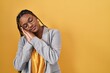 © Krakenimages.com - African american woman with braids standing over yellow background sleeping tired dreaming and posing with hands together while smiling with closed eyes.