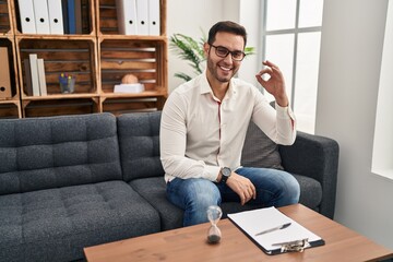 Sticker - Young hispanic man with beard working at consultation office smiling positive doing ok sign with hand and fingers. successful expression.