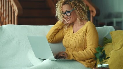 Wall Mural - One adult woman using computer at home sitting comfy on the sofa having relax and enjoying online technology surfing the web. Modern female people chatting and having fun alone indoor. Leisure