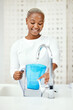 © Lategan/peopleimages.com - Water, filter and black woman at tap with jug for liquid purification, cold hydration and cooling bottle at home. Happy female person at faucet for pure aqua, clean treatment and pitcher for drink