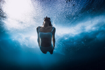 Wall Mural - Woman dive without surfboard underwater with ocean wave. Lady duck dive under barrel wave