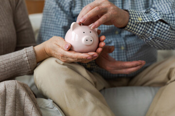 Saving money investment for future. Senior adult mature couple hands putting money coin in piggy bank. Old man woman counting saving money planning retirement budget. Saving investment banking concept