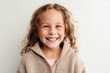© Hanne Bauer - Portrait of a smiling little girl in a sweater on a white background