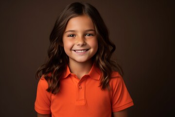 Portrait of a cute little girl in orange t-shirt on dark background