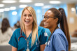 © MVProductions - Candid shot of two nurses laughing and talking in a hospital, showcasing positivity and collegiality. Generative AI