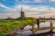 © Noppasinw - Dutch Windmill at Zaanse Schans Village with woman tourist, Amsterdam Netherlands