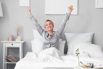 Wall Mural - Mature woman waking up in bedroom