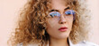 © Beauty Agent Studio - Trendy eyeglasses. Fashion outdoor portrait of a beautiful blonde young woman with curly hair wear transparent glasses and white jacked