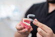 Doctor installing clear aligners on plastic lower human jaw model to show simple and effective device in stomatology clinic specialist performing teeth improvement