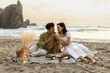 © Prostock-studio - Loving romantic couple having picnic on sandy beach near ocean, drinking wine and enjoying date at coastline, copy space