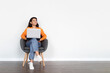 © Prostock-studio - Positive young eastern woman sitting in armchair, using laptop