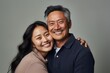 © Rodrigo - Happy asian father and daughter hugging and smiling at the camera on gray background. Ai generated.