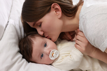 Wall Mural - Happy mother kissing her little baby on bed