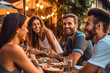 © MVProductions - Group of friends laughing and enjoying dinner at outdoor restaurant during summer, generative ai