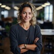 © Adriana - Smiling attractive confident professional woman posing at her business office with her coworkers and employees in the background