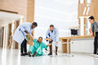© Kawee - Group of people help female patient falling on the ground in hospital.
