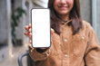 © Farknot Architect - Mockup image of a young woman holding and showing a mobile phone with blank white screen