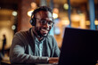 © Rafa Fernandez - African Man wearing headphones and working with laptop, smiling and looking at camera. AI Generative