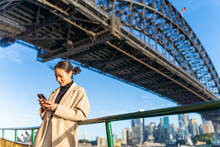 Asian Woman Using Mobile Phone During Travel On Ferry Boat Crossing Harbor In Sydney, Australia. Attractive Girl Enjoy Urban Outdoor Lifestyle Travel In The City With Gadget Device On Holiday Vacation