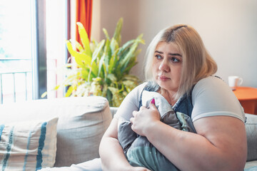 Sad plus size overweight woman cry and hug pillow at home. Depression, anxiety, social phobia and other mental problems.