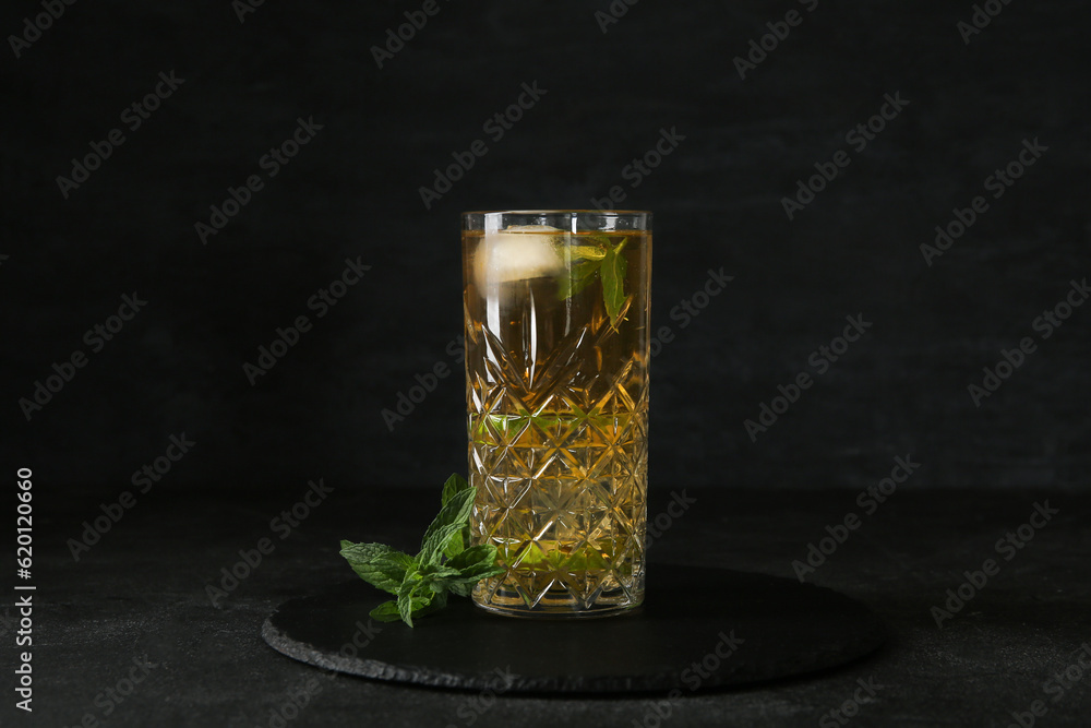 Glass of ice tea with mint on black background