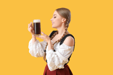 Beautiful Octoberfest waitress with beer on yellow background