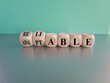 © Liudmila - Adaptable or reliable symbol. Turned wooden cubes and changed the word adaptable to reliable. Beautiful blue background, grey table, copy space. Business and adaptable or reliable concept.