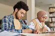 © AnnaStills - Multiethnic students writing foreign language exam at table in class