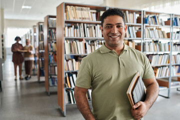 Portrait of adult student smiling at camera while standing in the library